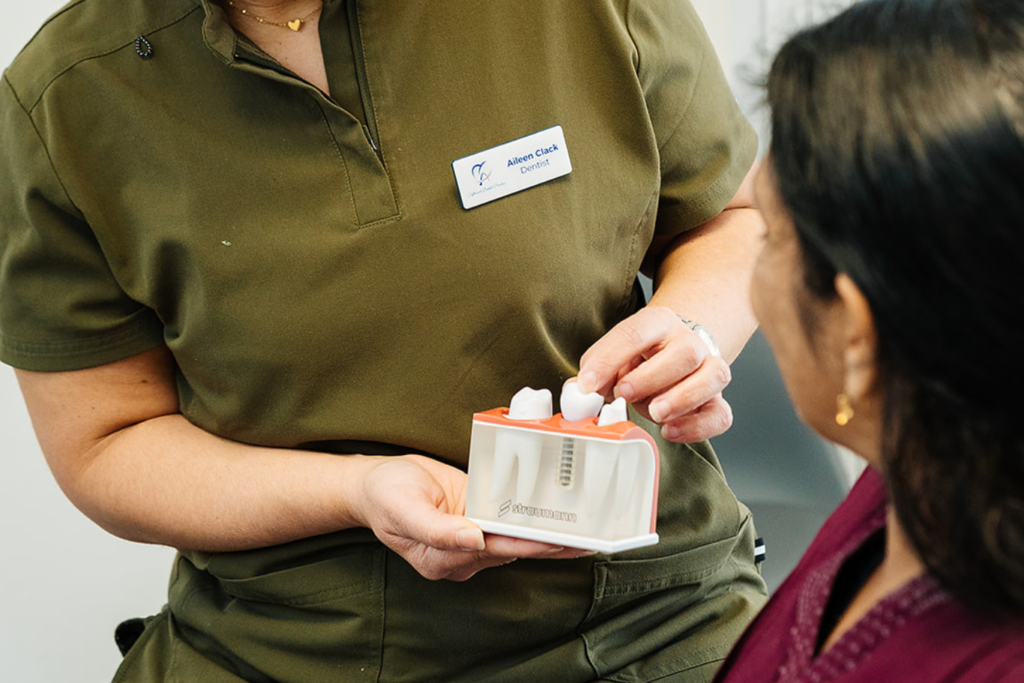 Dr Aileen Clack holding a dental implant typodont with a Straumann logo on it.